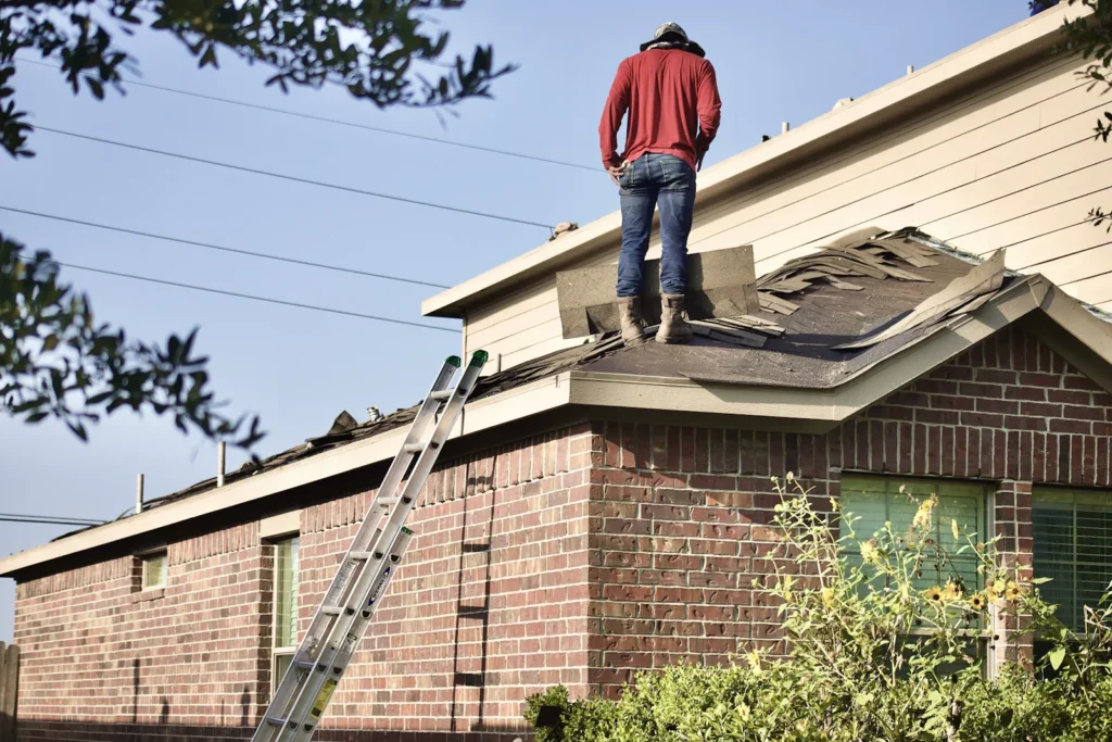 Inspector standing on a shingle roof beside a chimney